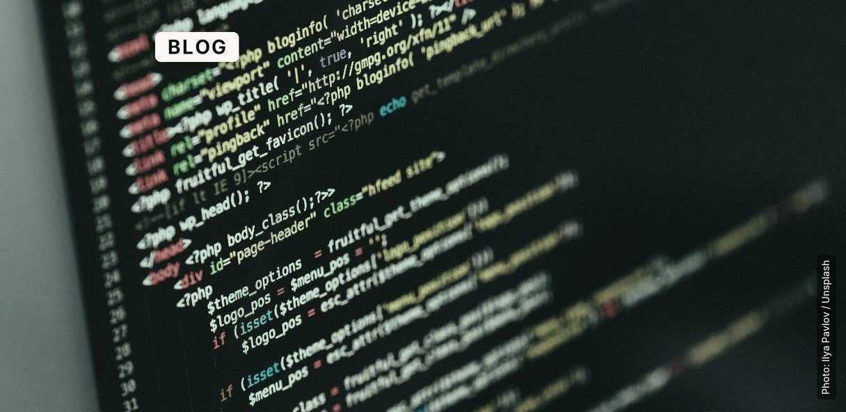 A monitor displays lines of source code