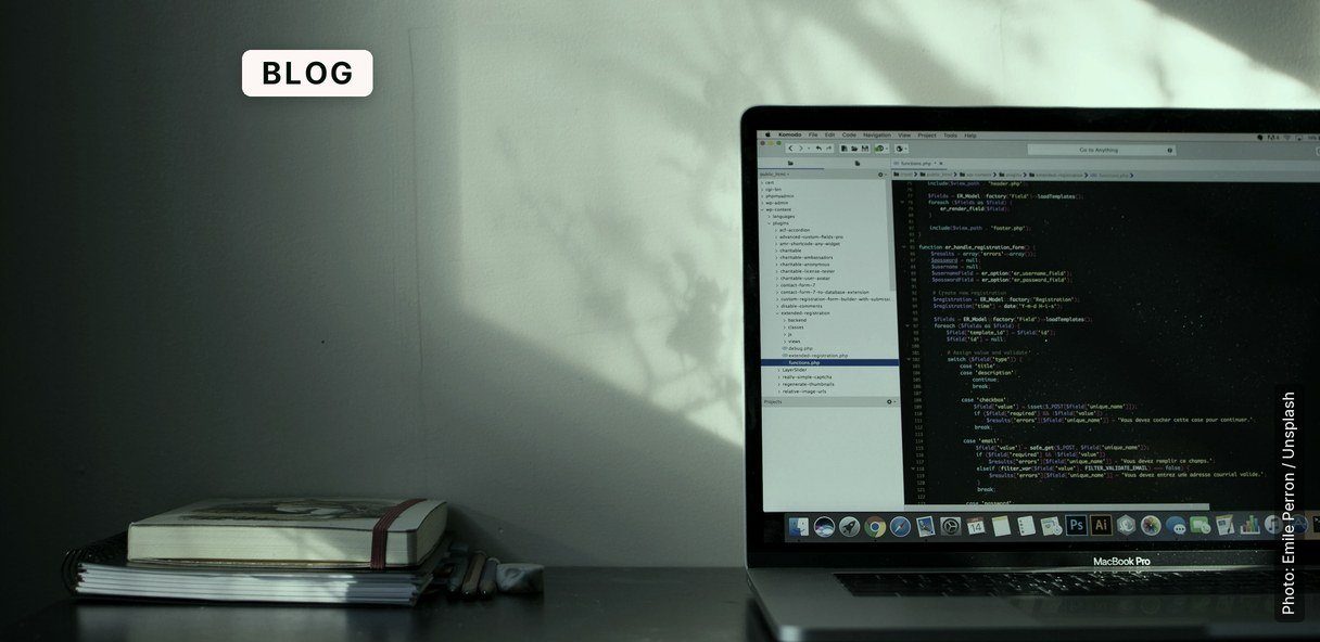 A MacBook Pro screen displays programming code